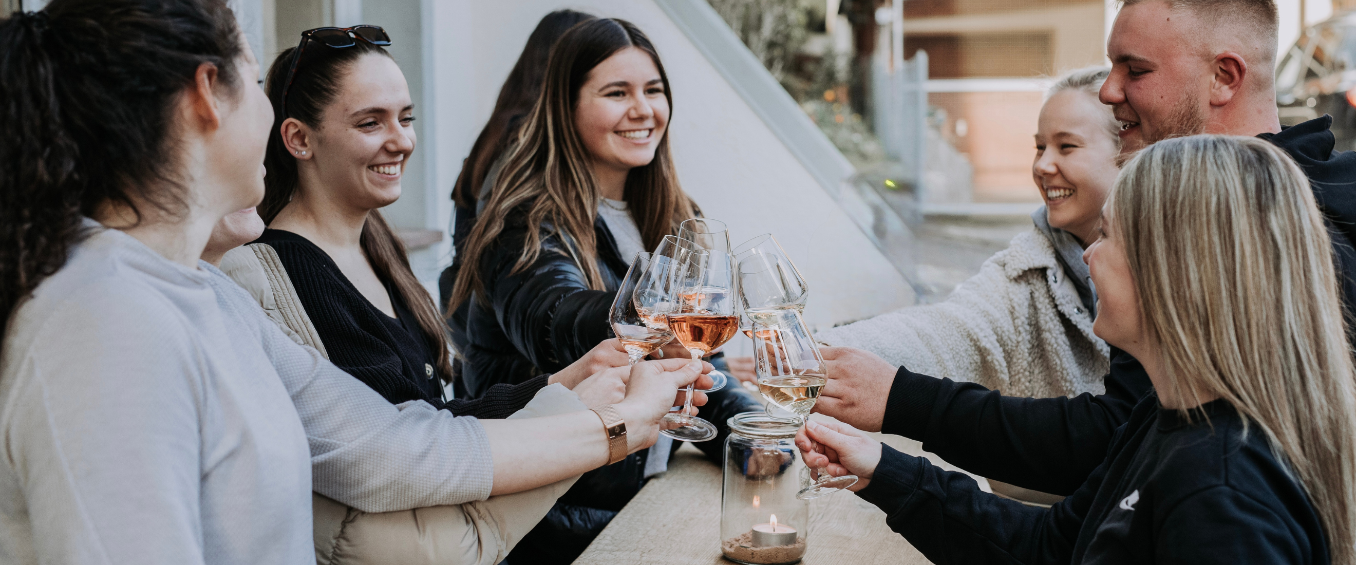 WeintrinkerInnen stoßen mit Weingläsern freudig an. 